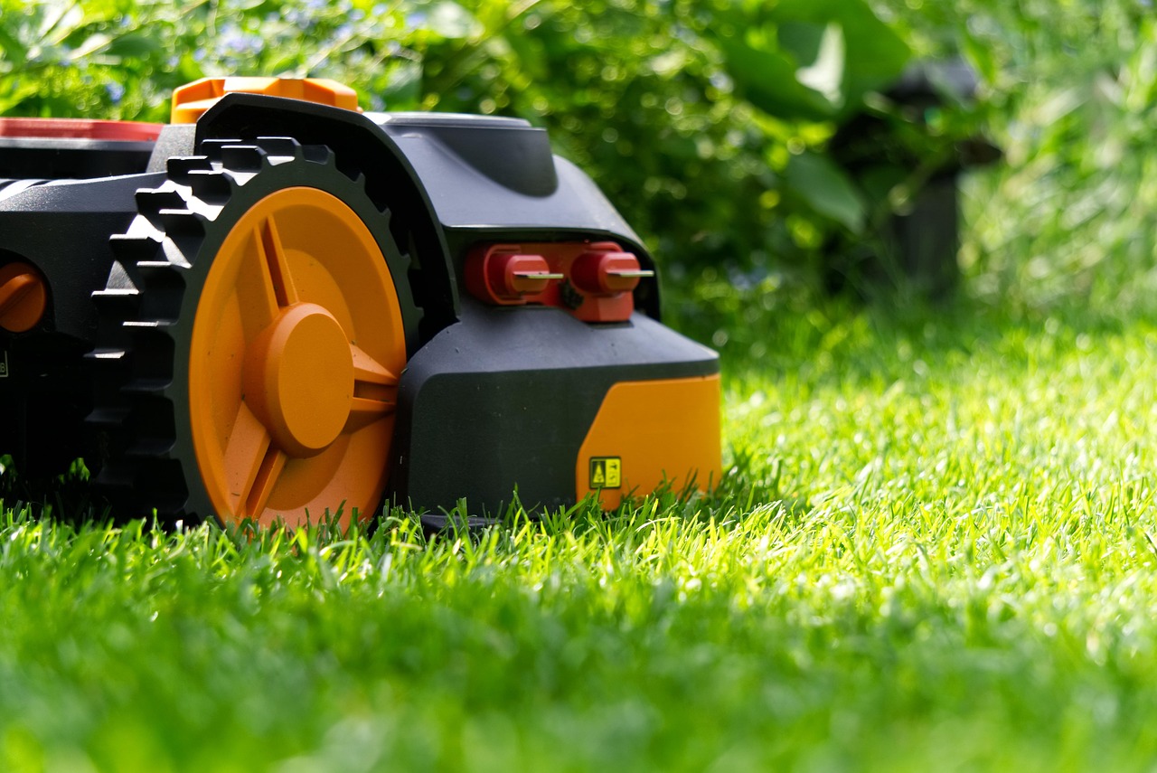 Robotmaaier trimt gras naast bloemenperk. Robotmaaier trimt gras naast bloemenperk.