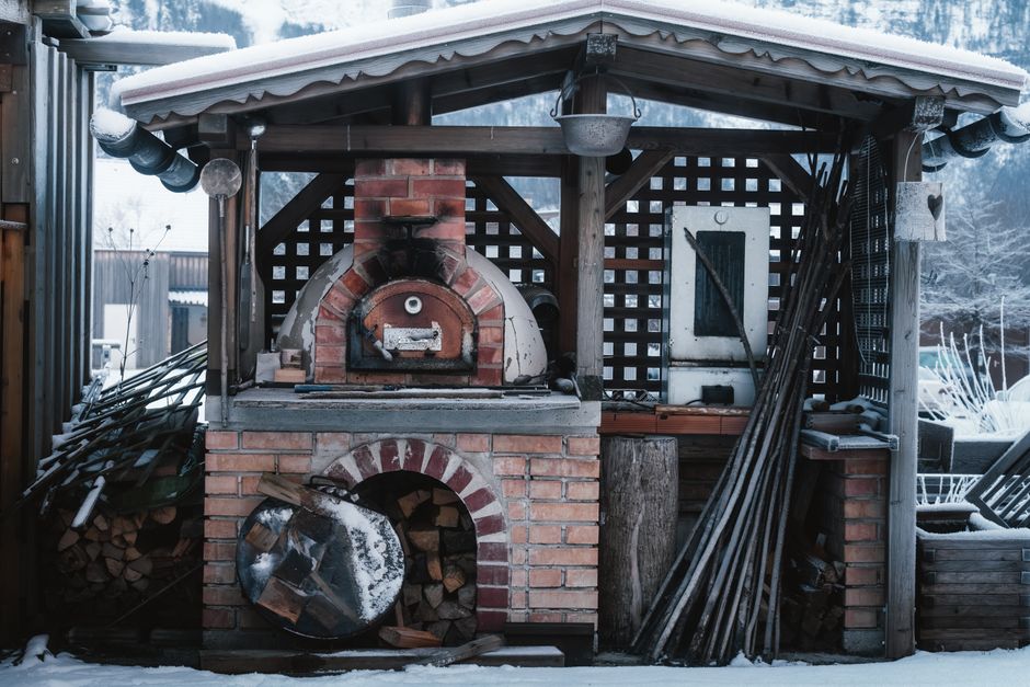 Man controleert gasfles in winterklare buitenkeuken.